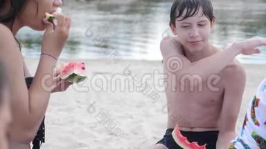 孩子们，青少年在海滩上休息，笑着<strong>吃西瓜</strong>，慢动作<strong>视频</strong>。 男孩和女孩的生活方式